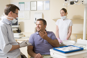 Man in dental chair talking to dentist