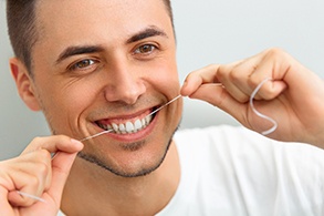 Man flossing around his dental implant in Salinas
