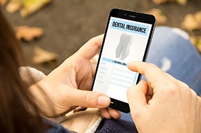 Patient looking at dental insurance form on phone outside