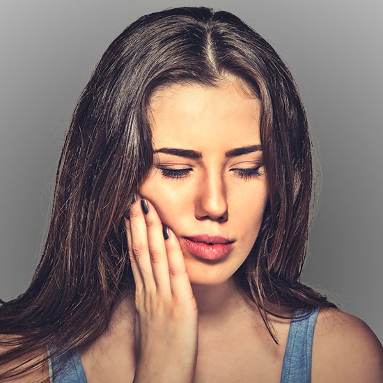 woman holding cheek in pain