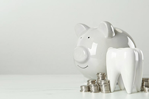 a piggy bank and coins next to a tooth