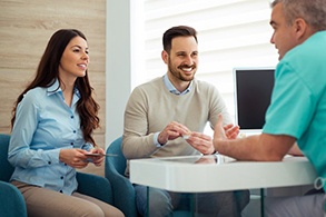 a couple speaking with their dentist about prices