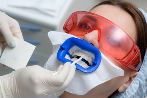a woman having her teeth whitened at a dental office