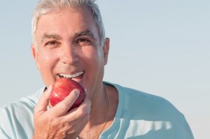 older man biting into apple