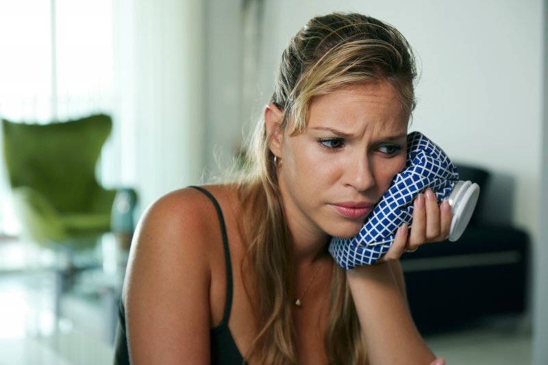 person holding ice pack against face after wisdom teeth removal