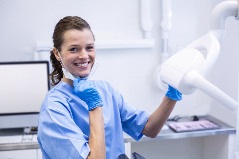 A smiling dental hygienist adjusting the lighting